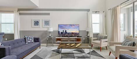 Un salon moderne avec un canapé, des fauteuils, une table basse et un téléviseur.