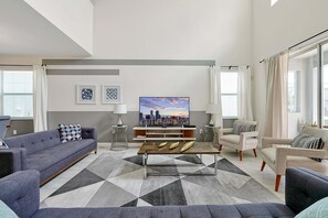 Ein stilvolles Wohnzimmer mit einer Couch, Sesseln, einem Couchtisch und einem Fernseher.