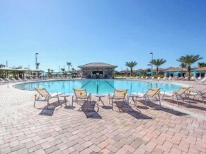 A pool area with lounge chairs and umbrellas, a covered seating area, and a clear sky. - Family & Dog-Friendly ChampionsGate Villa | Private Pool, Game Room & Themed Rooms (Champions Gate)