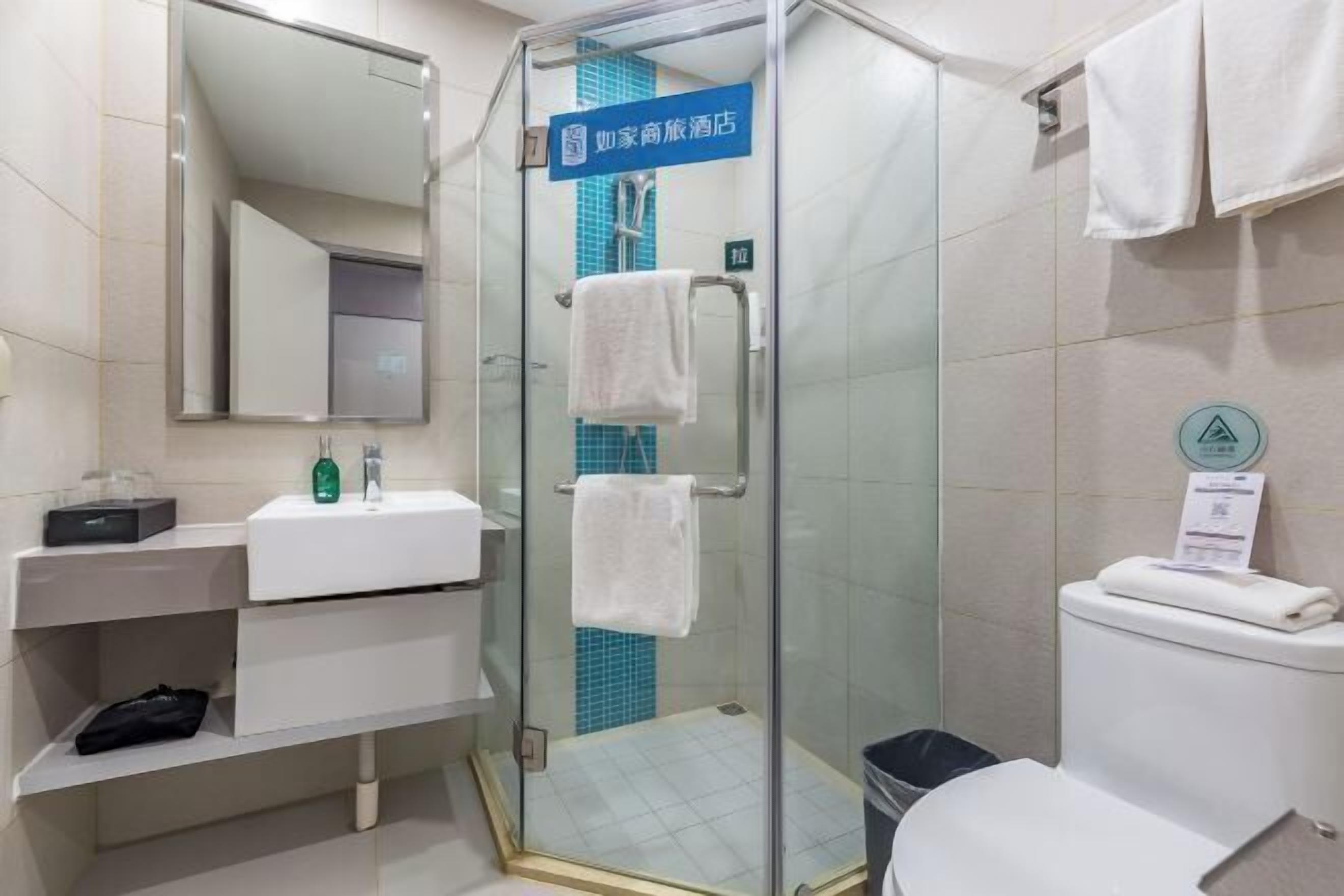 A modern bathroom with a glass shower enclosure, a sink with a mirror, and a toilet.