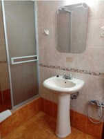 A bathroom with a white sink, a mirror above it, and a shower area with a glass door.