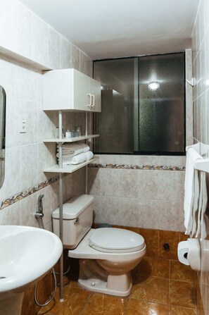 A bathroom with a toilet, sink, and shelves. - Xima Central Tacna (Tacna)