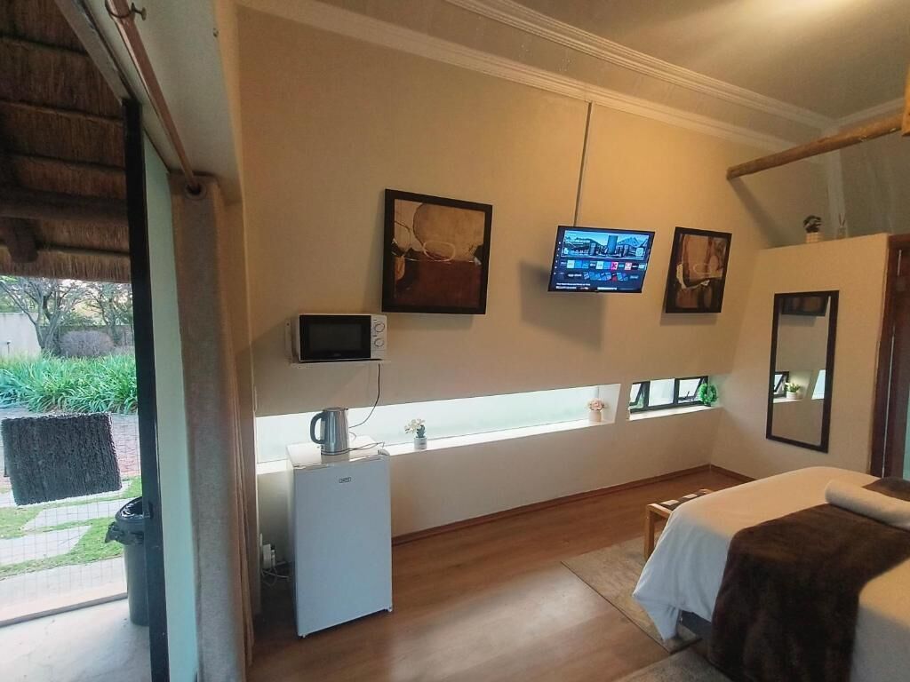 Une chambre d’hôtel comprenant un lit, un petit bureau avec une bouilloire, un téléviseur fixé au mur et une fenêtre donnant sur l’extérieur.