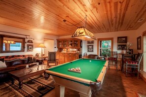 Um quarto aconchegante com mesa de bilhar, sofá e área de refeições.