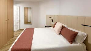 Une chambre d’hôtel avec un lit, une armoire en bois, un miroir et une table de chevet.