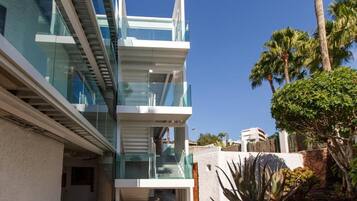 A modern multi-story building with glass balconies and a clear sky.