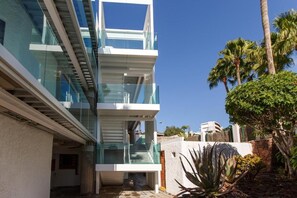 A modern multi-story building with glass balconies and a clear sky.