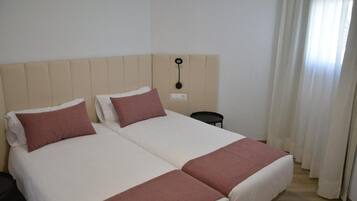 A double bed with two pillows, a bedside table, and a wall-mounted light fixture.