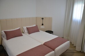 A double bed with two pillows, a bedside table, and a wall-mounted light fixture.