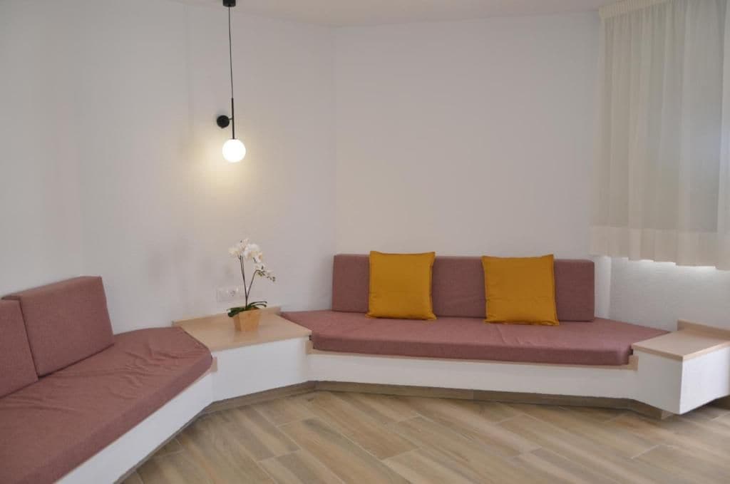 A modern living room with a pink sofa, a white coffee table, and a hanging light fixture.