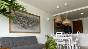 A modern living room with a grey sofa, white chairs, a round wooden coffee table with a plant, and a dining area with a white table and chairs. - Cartagena Frente a la Playa 27A (Cartagena)