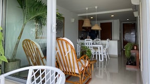 A modern living room with a glass door leading to a balcony, furnished with white chairs and a dining table. - Cartagena Frente a la Playa 27A (Cartagena)