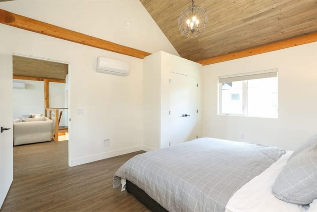 Ein Schlafzimmer mit einem Bett, Holzboden und einem Fenster.