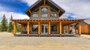 Una casa moderna de varios pisos con un porche de madera llamativo, ventanas amplias y un camino de entrada de grava.