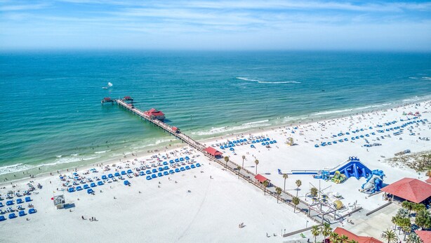 Ein Strand mit einem Steg, der ins Meer führt, einer Wasserrutsche und zahlreichen Strandsonnenwänden.