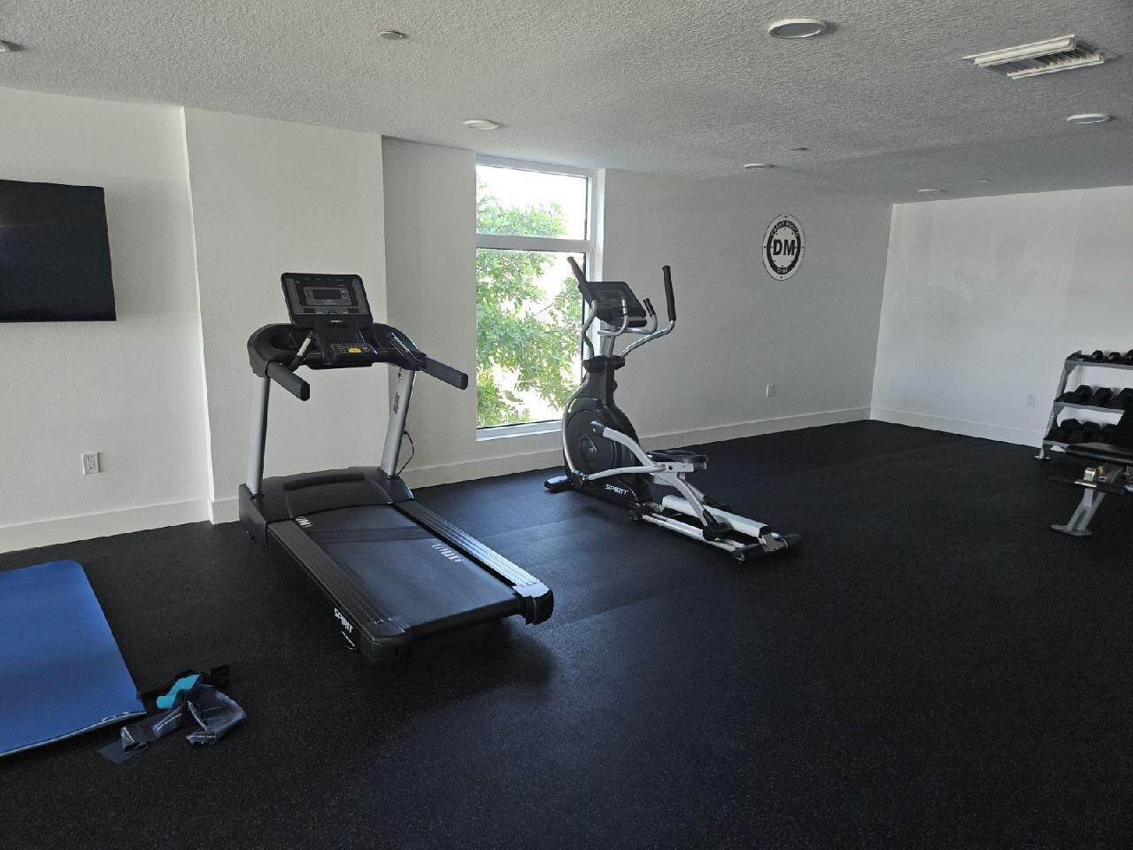 Un gimnasio con cintas de correr, elípticas y una banca de pesas.