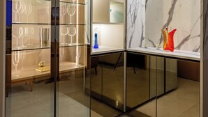 A modern interior with a glass-fronted wine rack, marble wall, and a small table with decorative items. - Modern Apartment with Fantastic View of the Flamboyant  (Goiânia)