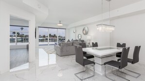 A modern dining area with a glass-top table, black chairs, and a hanging crystal chandelier. - 207, Water View-Clearwater Bch in 6 min, Pool/Gym (Clearwater Beach)