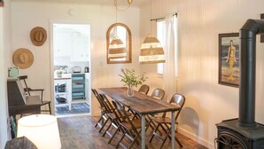 A dining area with a wooden table, chairs, and pendant lights. - The Sparrow Cottage (Bend)