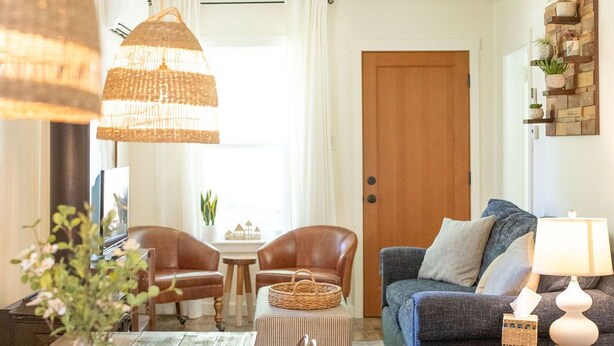 A dining area with a wooden table, chairs, and a hanging light fixture. - The Sparrow Cottage (Bend)