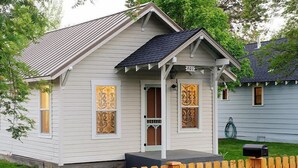 A small, single-story house with a porch and a wooden fence. - The Sparrow Cottage (Bend)