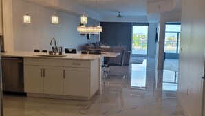 Una cocina moderna con una isla central, luces colgantes y vistas al exterior.