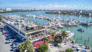 A marina with boats docked, a building with outdoor seating, and a parking area. - 403, Water View-Clearwater Bch in 6 min, Pool/Gym (Clearwater Beach)