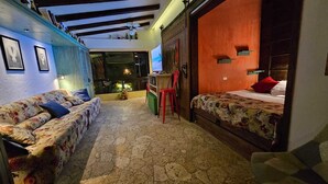 Una habitación acogedora con sofá, cama y una mesita. Se ve una ventana con vistas al exterior.