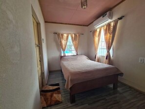 Relax in this serene bedroom with a comfortable bed, flanked by two windows and a textured ceiling.