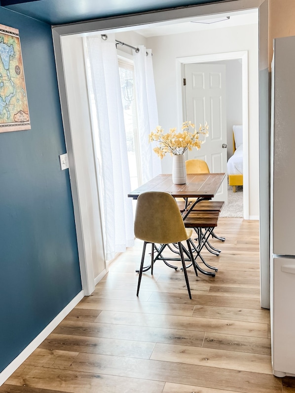 A dining area with a wooden table and chairs, a vase with flowers, and a map on the wall.