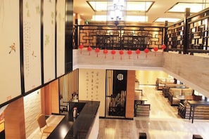A hotel lobby with a reception desk, seating area, and a staircase leading to an upper level. - Baodeli Hotel (Pan'an)