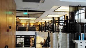 En moderne hotellobby med højt til loftet, en central trappe og en dekorativ hvid skulptur.