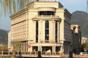 A classical building with a curved facade, large windows, and a prominent entrance. - Baodeli Hotel (Pan'an)