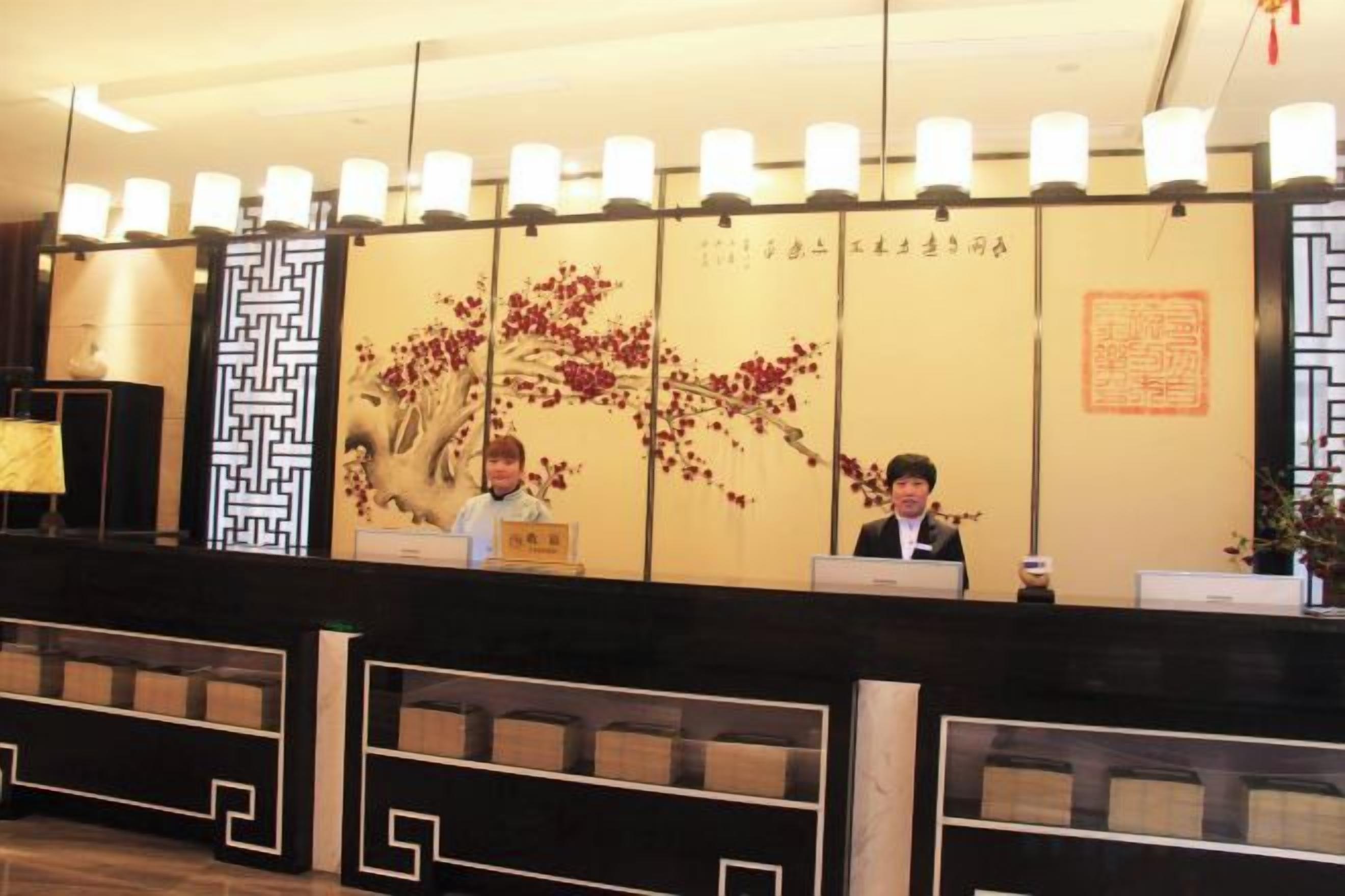 A reception desk with a decorative wall featuring traditional patterns and calligraphy.