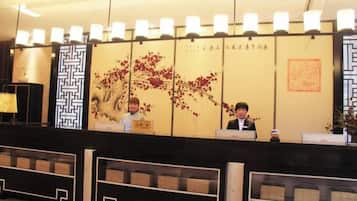 A reception desk with a decorative wall featuring traditional patterns and calligraphy.