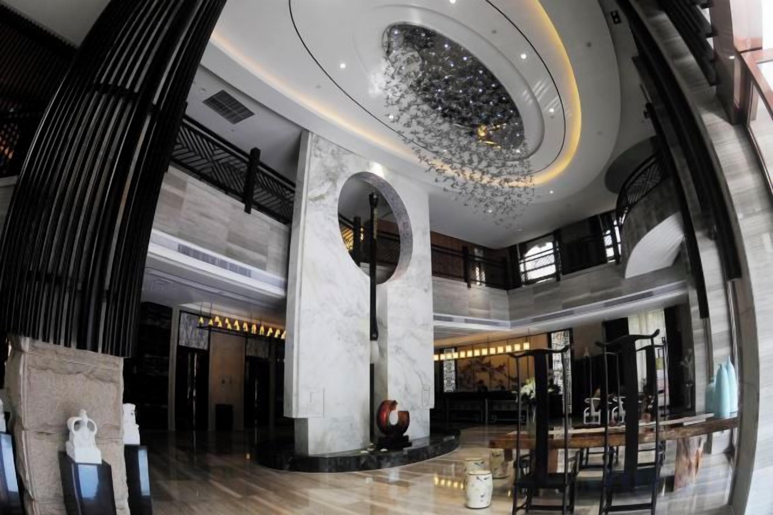 A spacious lobby with a high ceiling, marble flooring, and a central circular skylight.