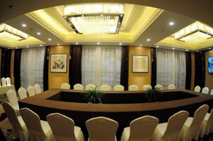 Uma sala de conferências com uma mesa redonda, cadeiras brancas e um lustre.