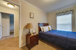 A bedroom with a bed, nightstand, lamp, and a window with blinds. - Family Home in Rapid City ~ 4 Mi to Torch Lake! (Rapid City)