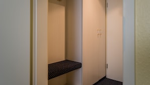 A narrow hallway with a small shelf and a door with a handle. - Point Hotel Apartments & Rooms (Dresden)