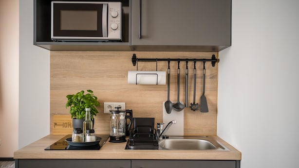 A modern kitchen with a microwave, coffee maker, and a sink. - Point Hotel Apartments & Rooms (Dresden)