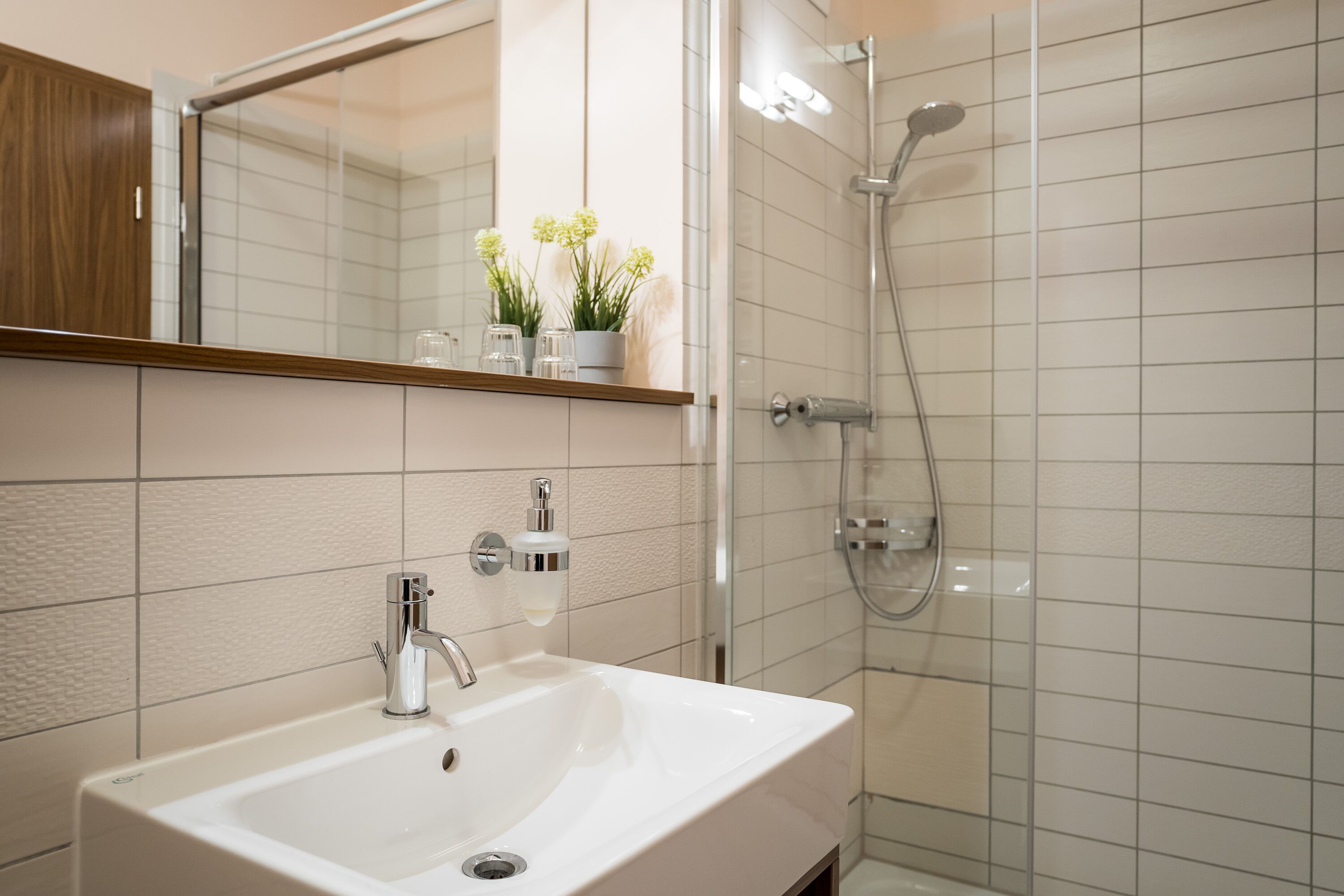 Ein Badezimmer mit Waschbecken, Spiegel, Dusche und Holzschrank.