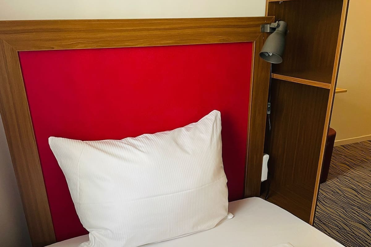 A neatly made bed with a red headboard and white bedding.