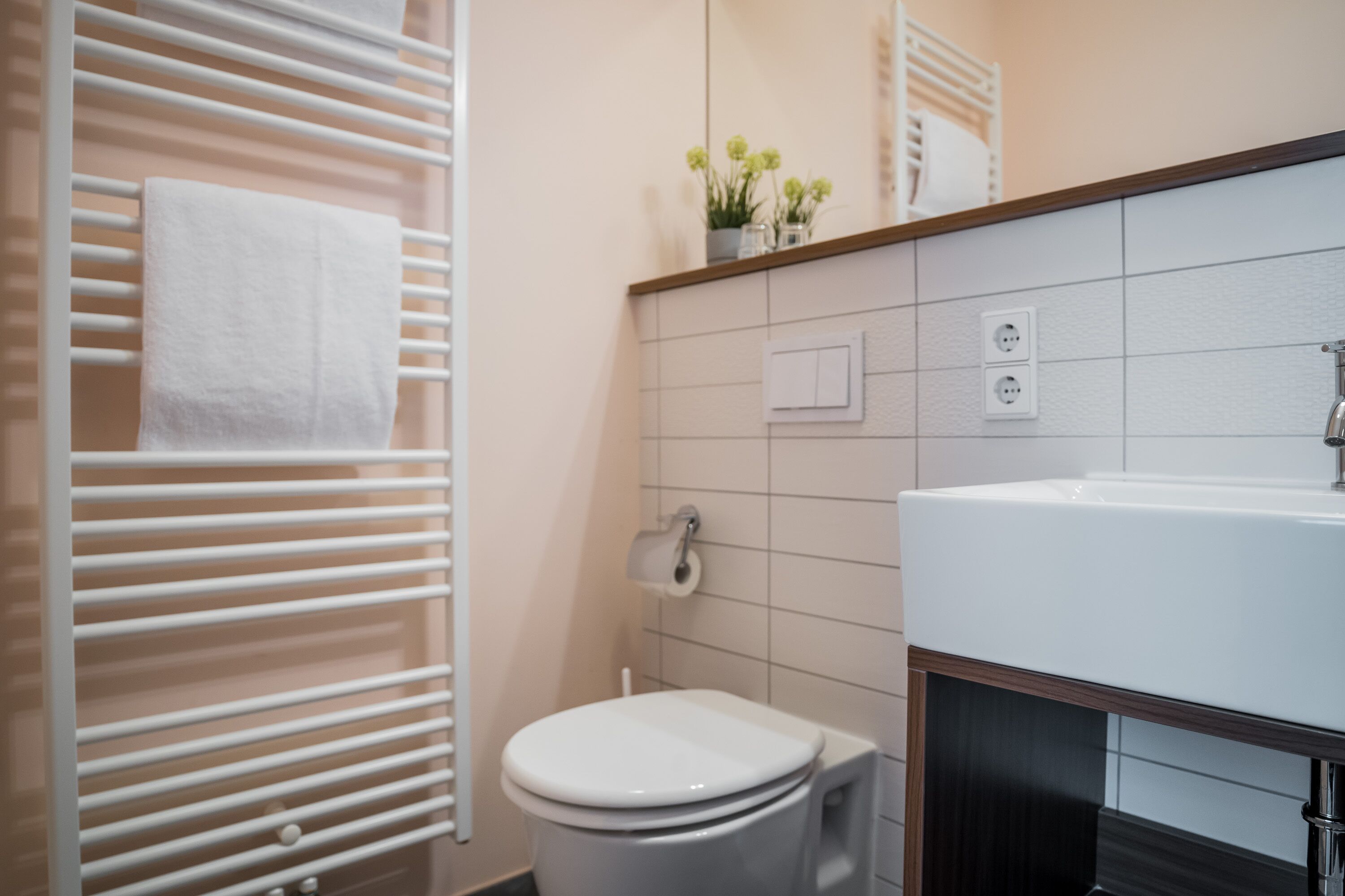 A modern bathroom with a white toilet, a sink, and a towel rack.