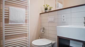 A modern bathroom with a white toilet, a sink, and a towel rack.