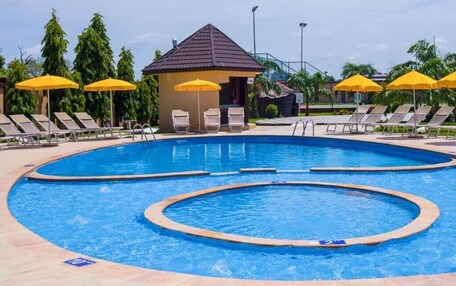 A swimming pool with multiple lanes, sun loungers, and yellow umbrellas.