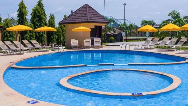 Une piscine avec plusieurs couloirs de nage, des chaises longues et des parasols jaunes.