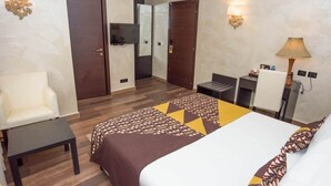 Une chambre d’hôtel avec un lit, un bureau, une chaise et un téléviseur.