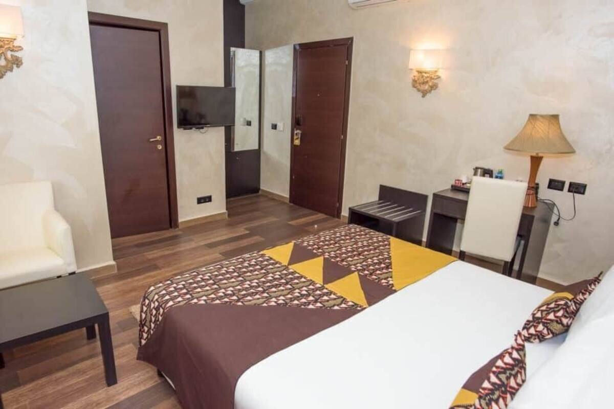 Une chambre d’hôtel avec un lit, un bureau, une chaise, une télévision et une lampe.