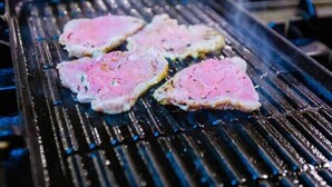 Un gril sur lequel sont en train de cuire plusieurs morceaux de viande.