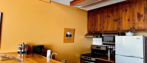 A kitchen with wooden cabinets, a microwave, a stove, and a refrigerator.